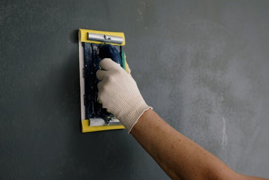 Professional plasterer smoothing wall surface with trowel during renovation in Milton Keynes